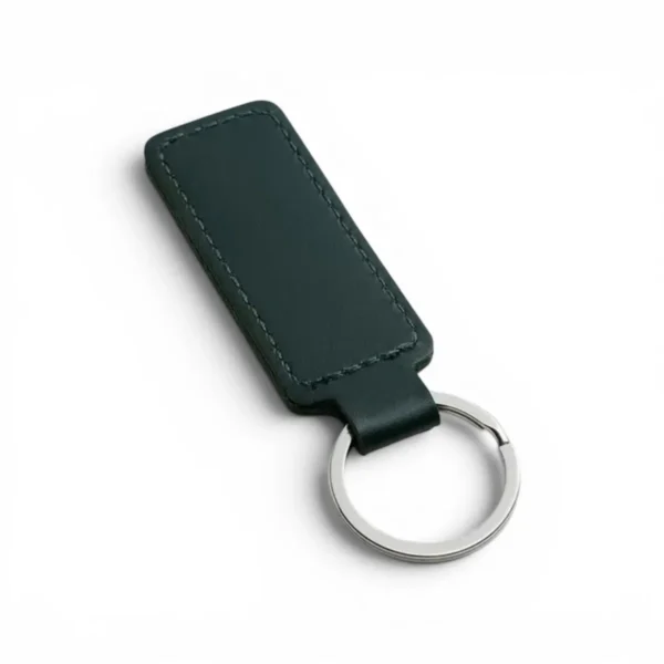 wikxy-laser-engraved-leather-keyholder-rectangular-shape-dark-green A dark green, blank premium leather keyholder before customisation, showcasing the raw stitching and thick leather grain on a wooden workshop table by WIKXY.